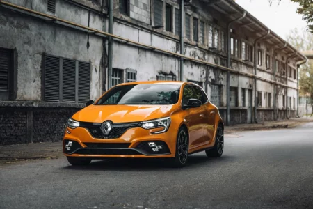 Neuer orangefarbener Renault Megane vor einem Industriegebäude – präsentiert vom Autohaus Auffenberg in Gelsenkirchen